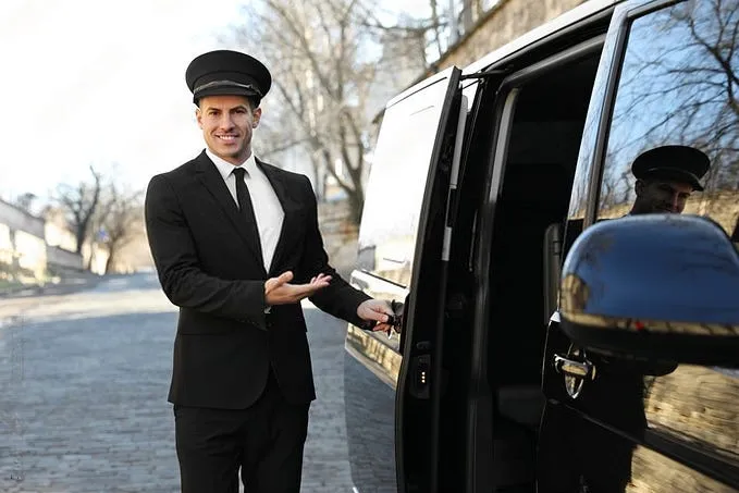 chauffeur of TaxiWithBabySeat.com greeting passenger and opeing the door for them to a Wedding Transfer trip
